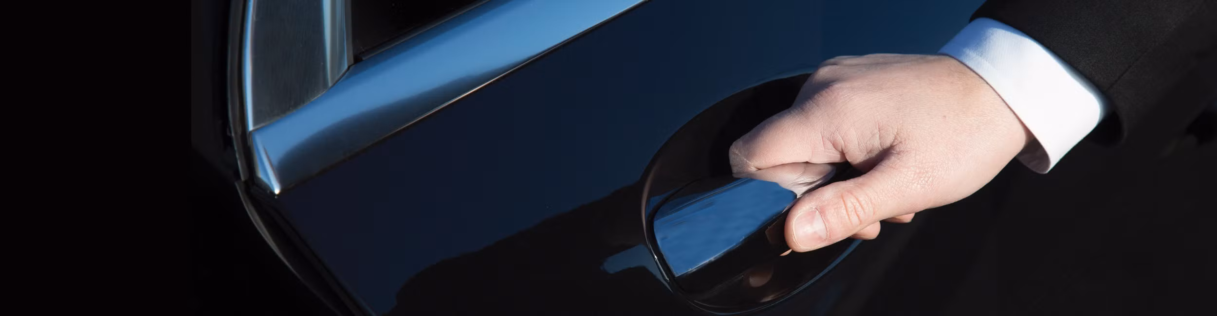 la main d'un chauffeur ouvre la portière d'une berline mercedes noire